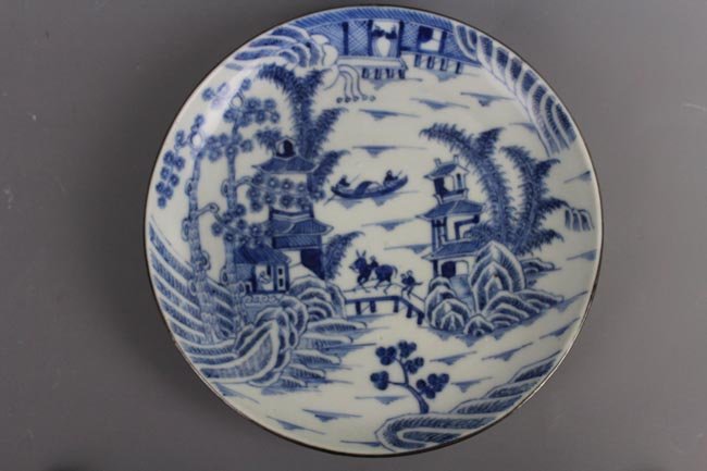 A Chinese Blue and White Blue de Hue Plate. Qing: Decorated overall with continuous landscape depicting figures going about their daily pursuits in a peaceful aura, Thien ha thai binh motif. The base displays a two characters mark, Ngoan Ngoc, typica