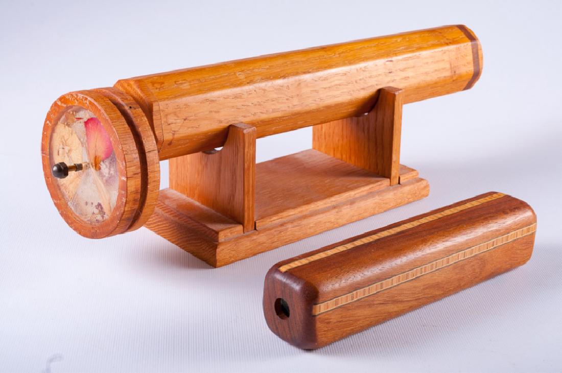 Brenchcrafted Wood Kaleidoscopes, Pair: Two benchcrafted wood kaleidoscopes, one with a double wheel and filled with dried flowers, includes a stand; the other of inlaid walnut containing a glass mirror prism. Largest measures approximately