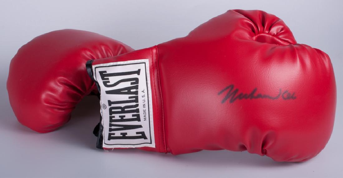 Muhammad Ali Signed Boxing Glove Set w/ COA: Pair of gloves, one signed "Muhammad Ali" complete with certificate of authenticity from James Spence Authentication (JSA). In acrylic display case, measuring approximately 9" high and 12-1/2" wide an