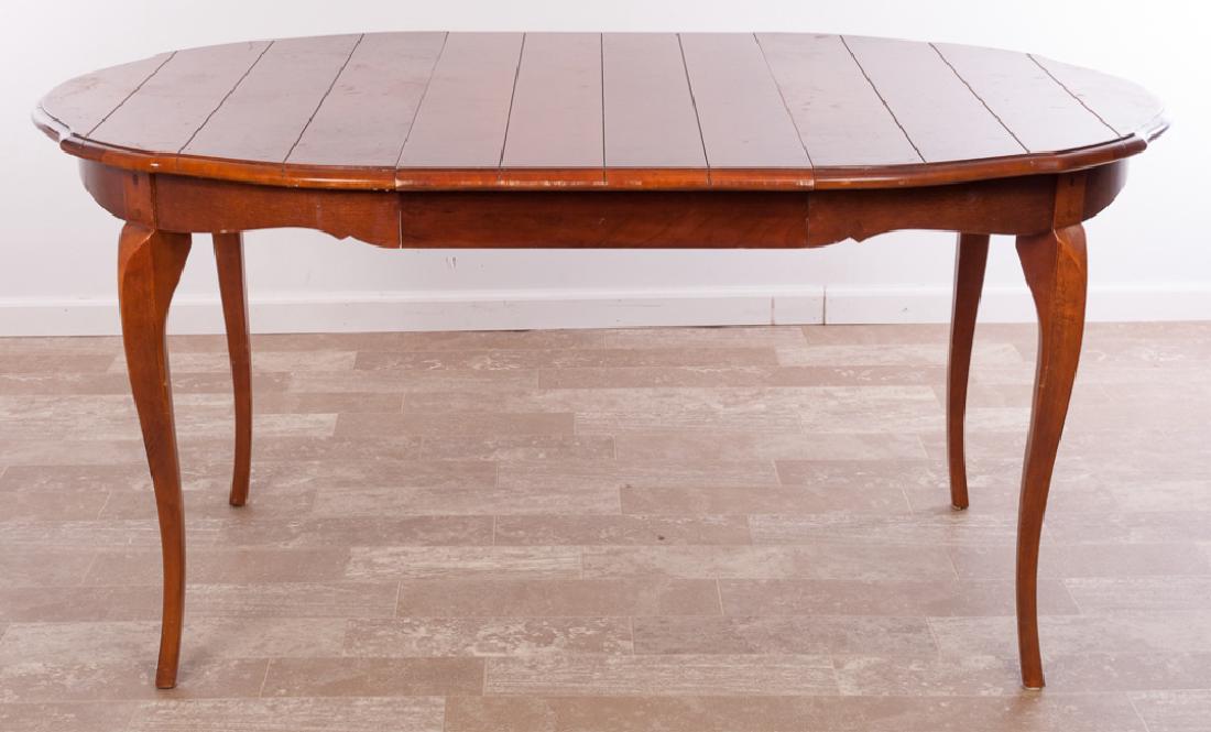 French Provincial Style Dining Table: Fruitwood French Provincial style dining table having a round top with shaped edge, shaped apron & tall French curved legs and one leaf; measures approximately 30-3/4" high and 43-5/8" in diameter, le