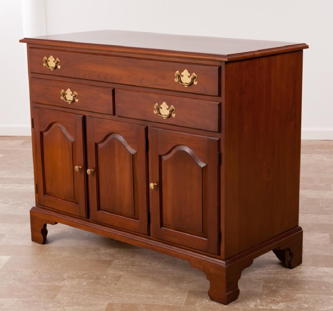 Henkel Harris Wild Black Cherry Sideboard: Henkel Harris solid wild black cherry sideboard having one long drawer over two drawers over three raised panel doors opening to a shelf and storage space with brass hardware and bracket feet; measure