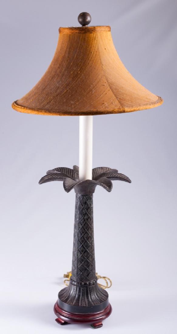 Palm Tree Candlestick Table Lamp: Candlestick table lamp having a faux white candle shaft and a metal palm tree form base mounted on a wood base; measures approximately 31” high and 5-7/8” in diameter to the base.