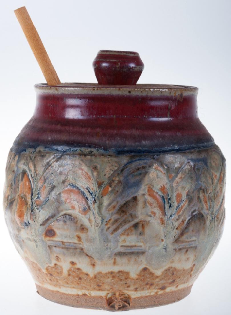 Earthenware Pottery Honey Pot: Earthenware lidded honey pot with wooden dipper; measures approximately 4-3/4” high and 4-1/2” in diameter. Illegibly marked to the side.