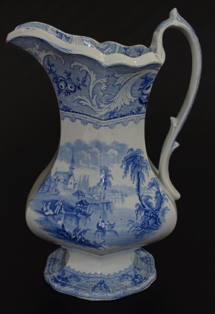 English Ironstone Pitcher, Late 19th Century: Late 19th Century English ironstone pitcher, blue transferware with a lake design; measures approximately 11-3/8” high, and 8-1/2” wide from spout to handle. Marked “Lake” to the bottom.