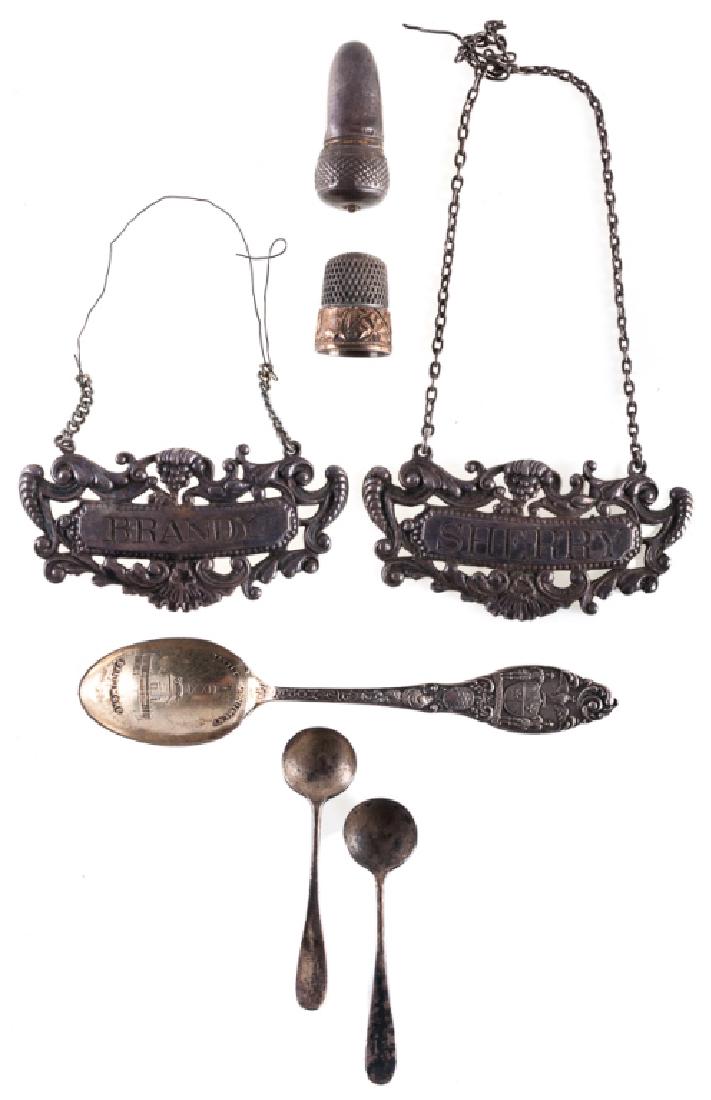 Sterling Silver Bar Accessories, 7 p.: Sterling silver group of seven (7) items to include: two (2) decanter labels, one (1) labeled Sherry, and one (1) labeled Brandy; two (2) small salt spoons; a souvenir spoon; a thimble; and an acorn f