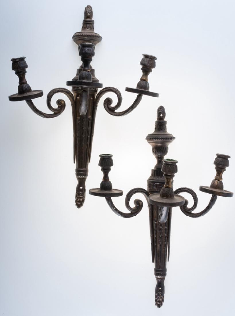 Brass Candelabra Wall Sconces Pair: Pair of three-arm antique candelabra wall sconces with brass candle brackets; each measure approximately 15-3/4” long and 11-1/4” wide. Provenance: from the Charlottesville, VA estate of Gene B. B
