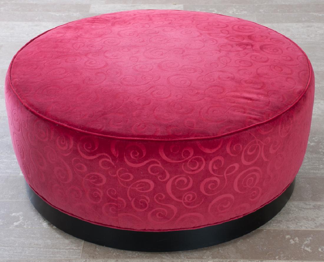 Cocktail Ottoman by McCreary Modern Inc.: Cocktail round ottoman covered in a ruby red colored fabric on a wood base with casters; measures approximately 16” high and 38” in diameter. Marked with tag to the underside of ottoman.