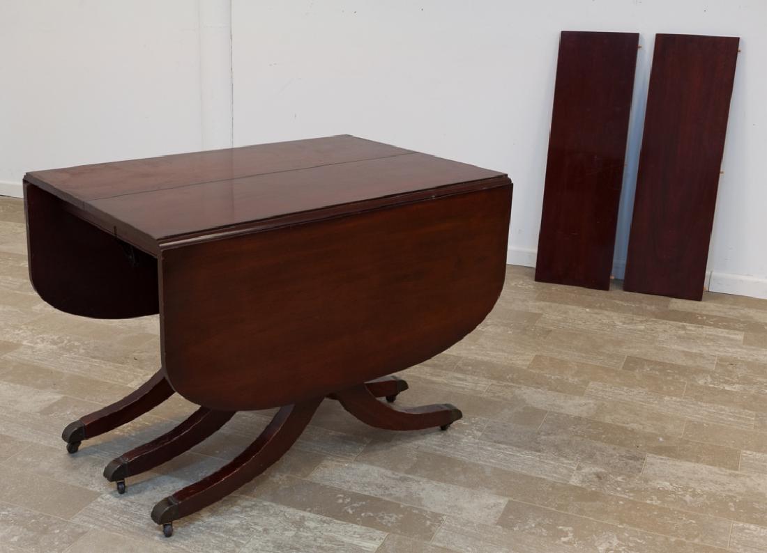 Duncan Phyfe Style Dining Table: Circa 1950 mahogany Duncan Phyfe Style drop leaf dining table resting on triple slayed legs with brass cap feet on casters, with two leaves; measures approximately 29-3/4" high, 40" wide, 26-1/4" long