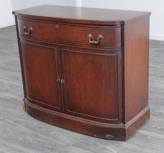 Landstrom Furniture Mahogany Server: Mahogany bow front server having a single drawer over two lower doors opening to a shelf, with brass pulls, and resting on a molded base. Marked Landstrom Furniture to the inside of drawer. Condition