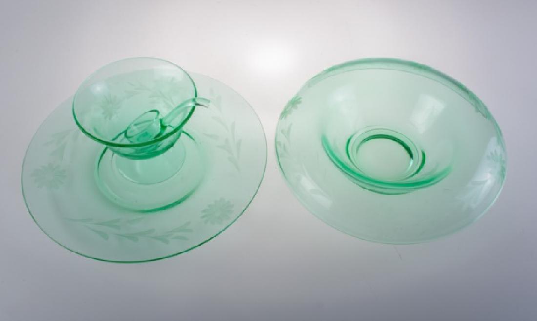 Green Depression Glass Group: Engraved floral design green depression glass group to include: one rolled edge centerpiece bowl, one large serving plate / underplate, and one sauce bowl with ladle. Fluorescent under ultraviolet lig