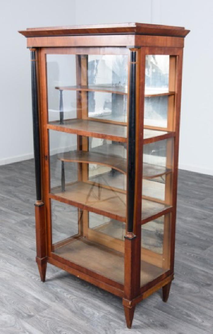 Biedermeier Vitrine / Display Cabinet: Biedermeier display cabinet having four interior shelves, two of the shelves are shaped and with column supports, original mirror to the inside back, front glass door flanked by ebonized columns on bl