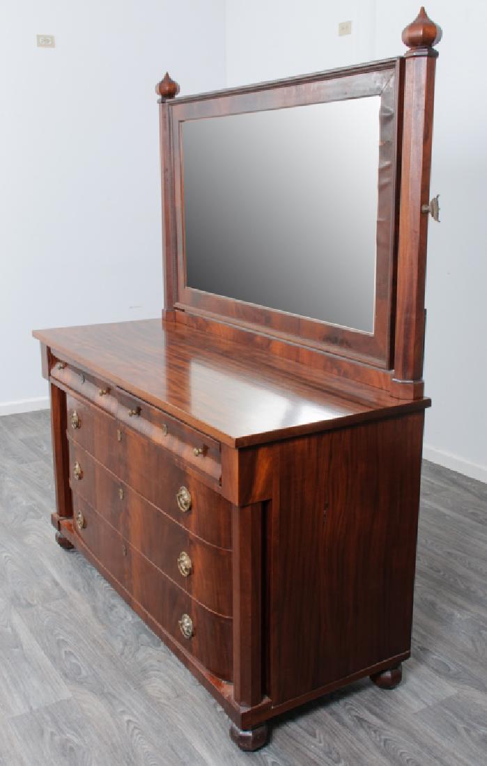 Mahogany Empire Dresser with Mirror: Mahogany Empire dresser and tilting mirror. The dresser having two ogee front drawers over three graduated drawers with curved ends, octagonal side columns and feet. The titling mirror having peaked o