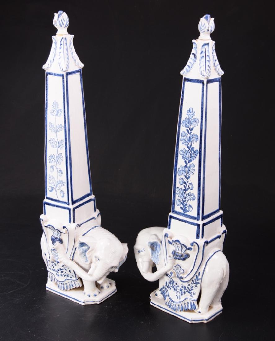 Blue and White Porcelain Obelisks: Pair of large blue and white porcelain elephant obelisks, with a floral motif, supporting tapering columns with removable stoppers. Marked to bottom "Made in Italy". Chipping to one. Measuring approxi