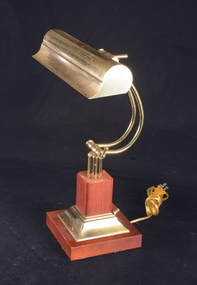 Brass Piano Lamp: Adjustable lamp with brass shade and wood base. At the time of cataloging lamp in good working Measures approximately 18-1/4" high, and 6-1/2" square to the base. All sales are subject to Bremo Auctio