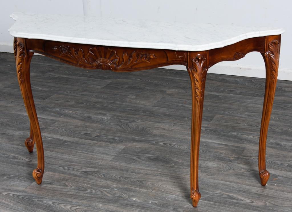 Marble Top Console Table: Console table having a shaped marble top with a molded edge, shell and floral carvings to the apron, acanthus carvings to the top of the French curved legs and ending in curled feet. Condition consist