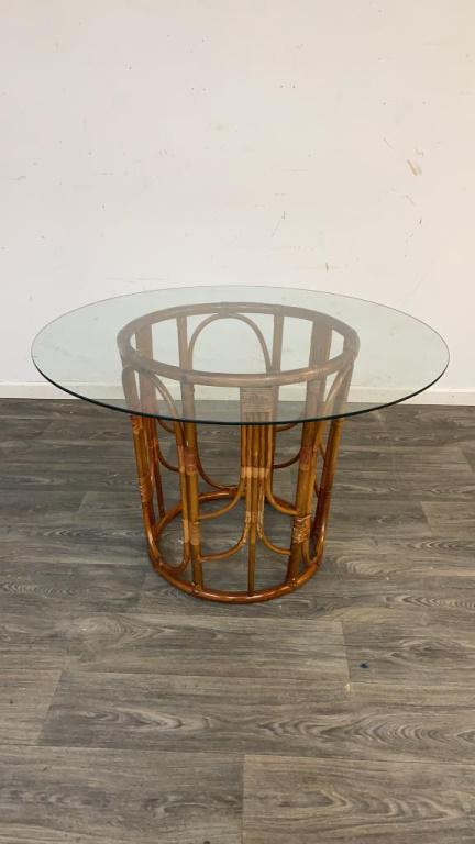 Glass Top Table: Round glass top sitting on rattan base. In overall good condition consistent with age and use. Measures approximately 28-1/2" high, 41-5/8" in diameter.