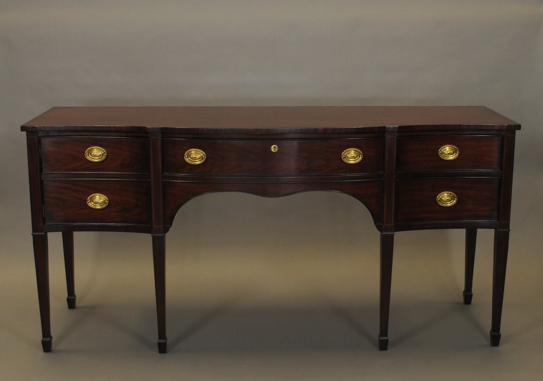 A Kindel Federal-style Mahogany Sideboard,: with a serpentine front top over a conforming front, with a single drawer flanked by two drawers and a faux drawer front door, all with cockbead moldings, over a scalloped apron and square tapered leg