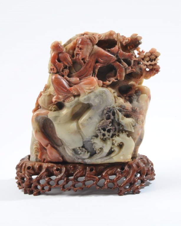 An Elaborate Chinese Soapstone Carving: A traditional carving of a Sage with student on a mountain/ocean wave mounting with pine trees, fish, octopi, basket, etc. 8-1/2" high, 9-3/4" wide, 3-1/2" deep.