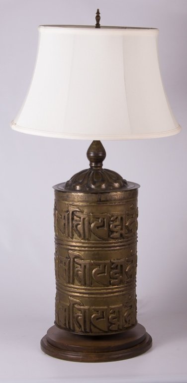 Tibetan (Nepalese) Prayer Wheel Lamp: Very unique bronze Tibetan Prayer Wheel converted lamp complete with Ranjana script; turns on a round wooden base and features a white shade; measures approximately 39" tall and 13" in diameter to bas