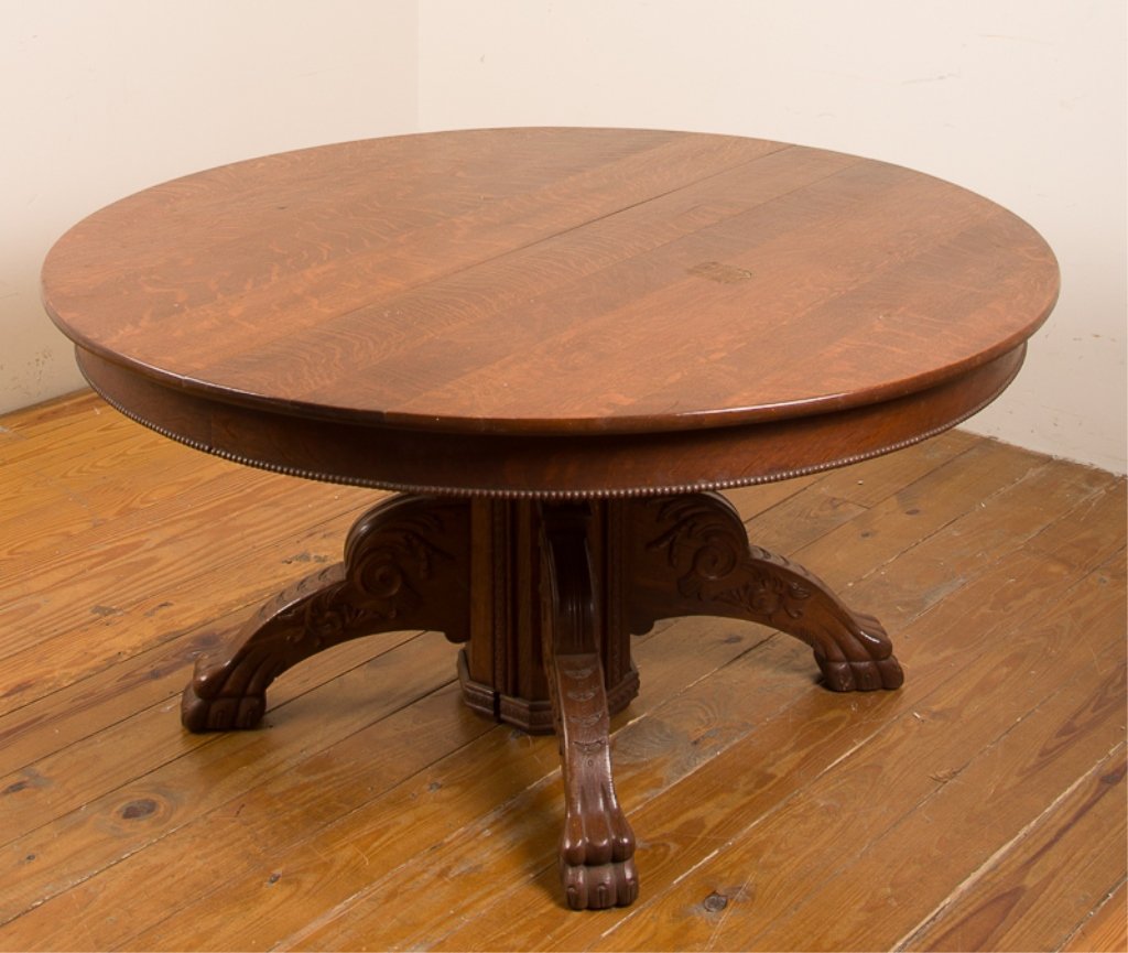 Tiger Maple Pedestal Dining Table: With two leaves; features decorative beadwork carving to lower rim and claw feet with elaborate carvings to legs; measures approximately 27-3/4" tall, 54" in diameter, and 76-1/2" long with leafs inse