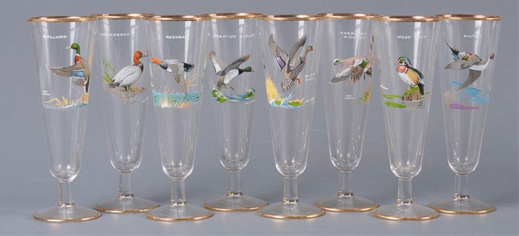 Ned Smith Pilsner Glasses, Eight (8): A set of eight footed Pilsner beer glasses from the Waterfowl series by noted wild life artist Ned Smith and accented with gold trim to rim and base. Each has the name of the bird printed on the glass