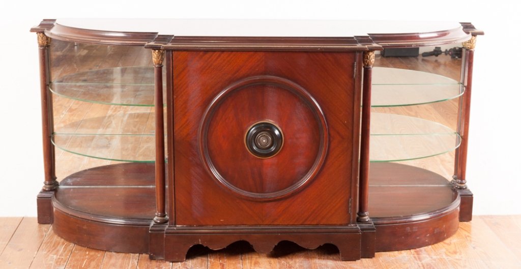 Mahogany Credenza: Mahogany credenza having shaped top with inlay, banded gold accent edging, fitted central door flanked by mirrored back, glass corner shelves and acanthus columns; measures approximately 36" high, 77"