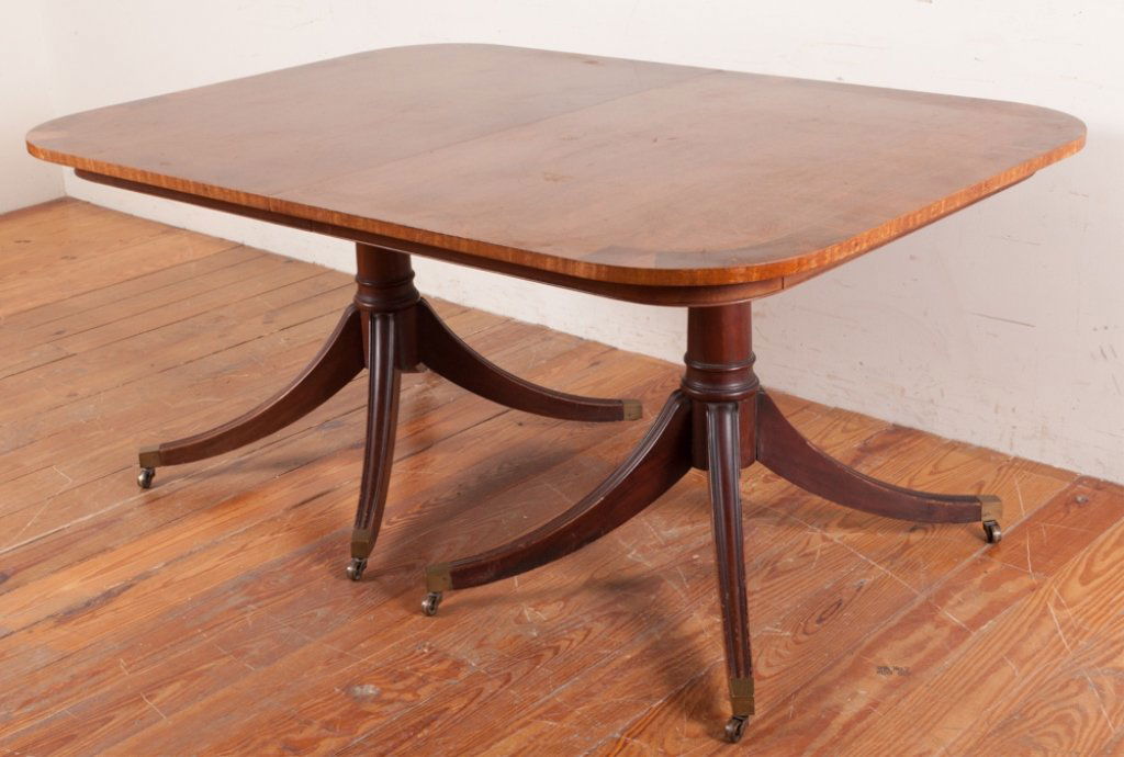 Duncan Phyfe Style Dining Table: Duncan Phyfe style double pedestal mahogany dining table with banded and string inlay to the top, three leaves, tapered and turned columns, and splay legs ending in brass feet on casters; measures app