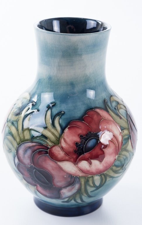 William Moorcroft Pottery Vase, Signed: William Moorcroft high glaze pottery vase having a blue/green ground exterior with poppy and anemone decorations and a deep blue interior ground; measures approximately 7-1/4" tall and 2-3/4" in diame