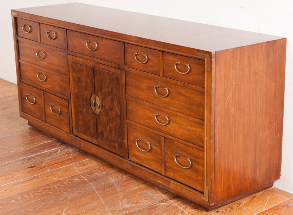 Thomasville Credenza Chest: Thomasville credenza chest having seven exposed drawers, two burl wood veneer center doors opening to two hidden wardrobe style drawers, Asian aesthetic brass pulls and accented campaign corner straps