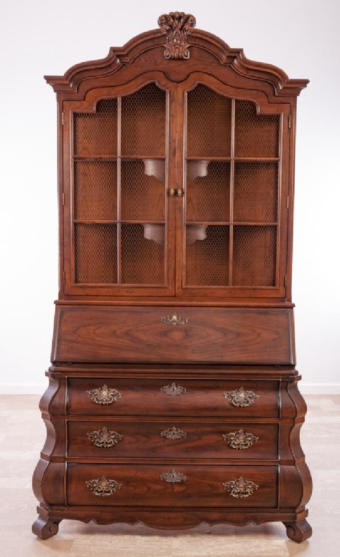 Henredon Secretary/Bookcase of Bombé Form: Henredon Four Centuries secretary/bookcase with a shaped molded arched cornice having a hand-carved crest, surmounting an upper case housing two shaped doors inset with French wire, opening to a shelv