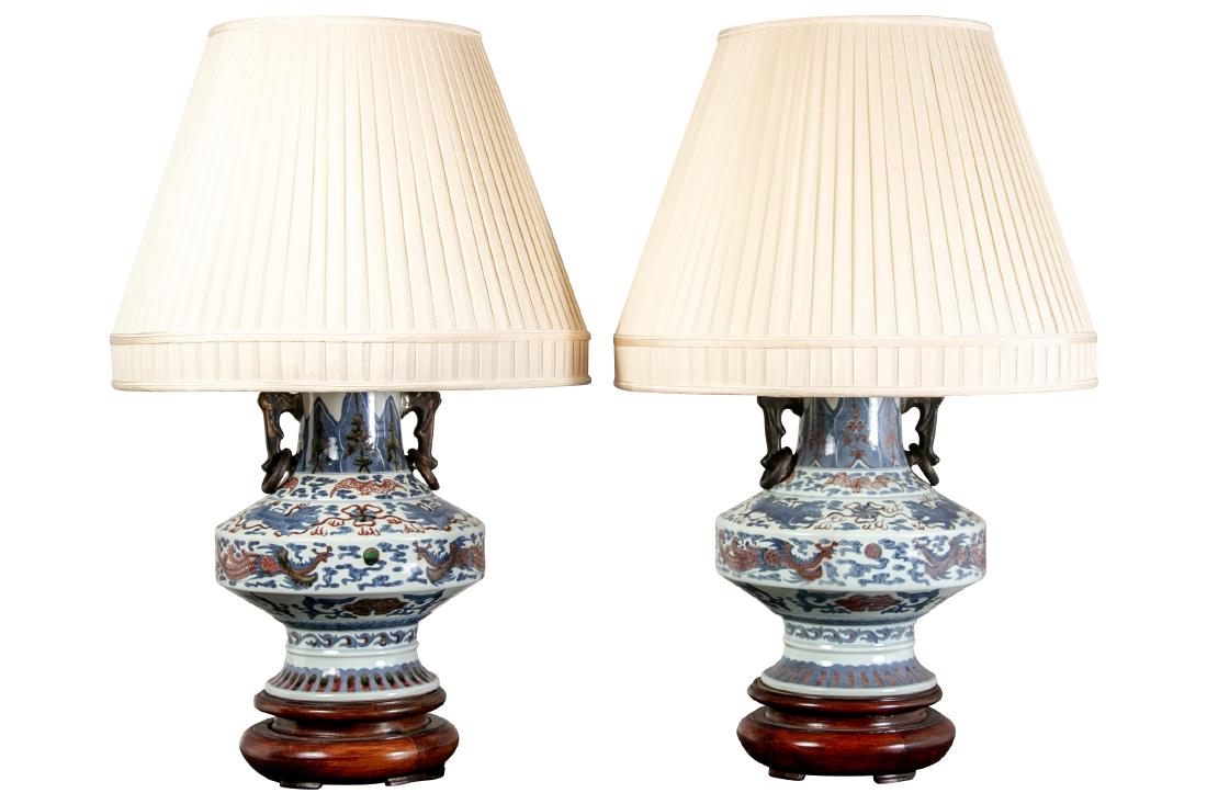 Pair Of Chinese Urn Form Table Lamps: Pair of Chinese urn form table lamps in blue and rust, having an all over pattern of dragons and florals, bronze side ring pulls, beehive form finial, adjustable standard, 2 chain operation, mounted o