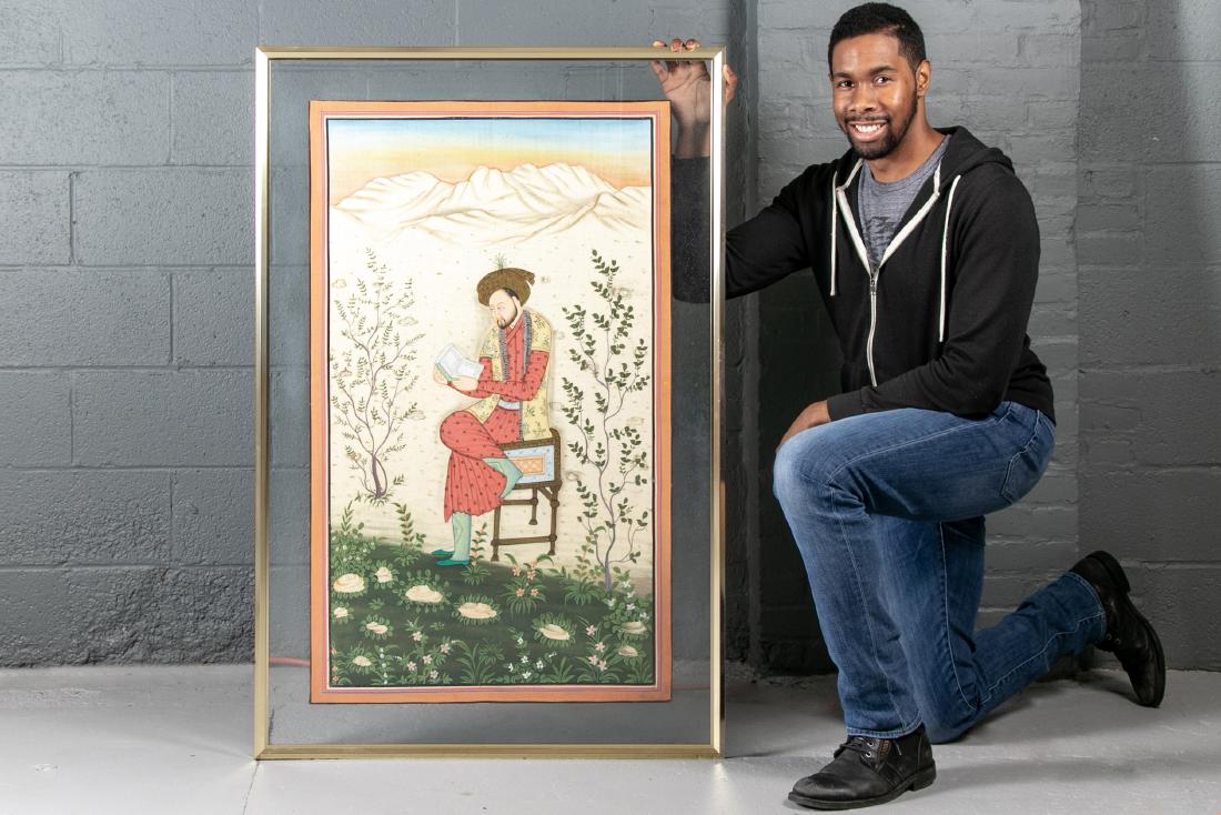 Mughal Style Gouache Figural Painting: An Indian Mughal style gouache and ink painting on silk blend fabric illustrating a casually seated gentleman in scholarly pursuit. He is flanked by trees and flowers with a landscape background at su