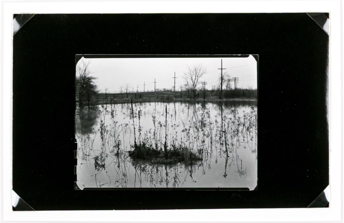 Harry Callahan (American, 1912-1999) "Detroit" Gelatin Silver Print: Harry Callahan (American, 1912-1999) "Detroit" gelatin silver print depicting a view of a pond dotted with vertical stems around a small clump island echoing telephone poles running across a grassy fi