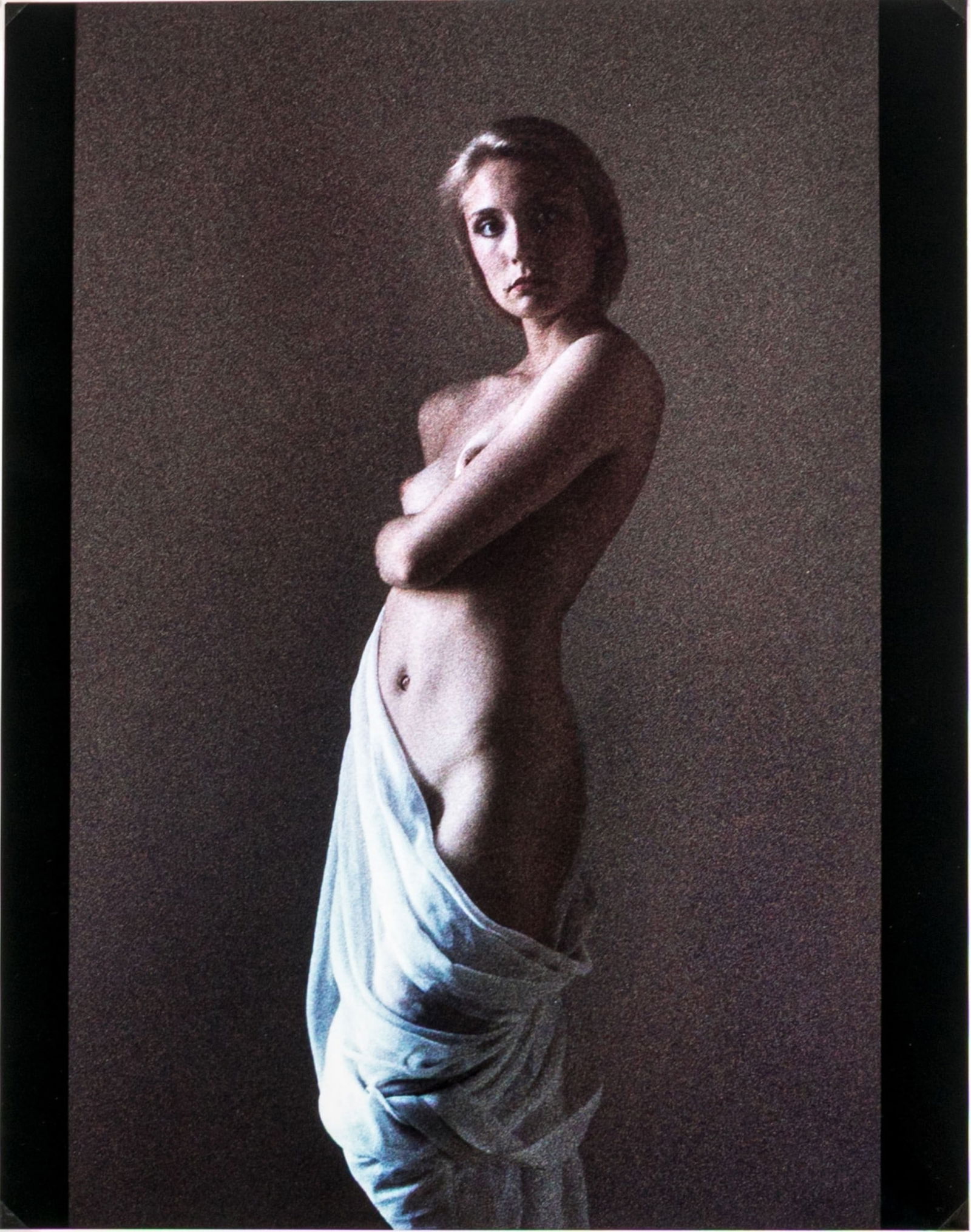 Linda Sutton "Venus Veiled" Cibachrome Print: Linda Sutton "Venus Veiled" cibachrome print depicting a female nude posed in three quarter profile with one arm wrapping around her waist, draped in pale fabric against a dark ground. Ink signed, tit