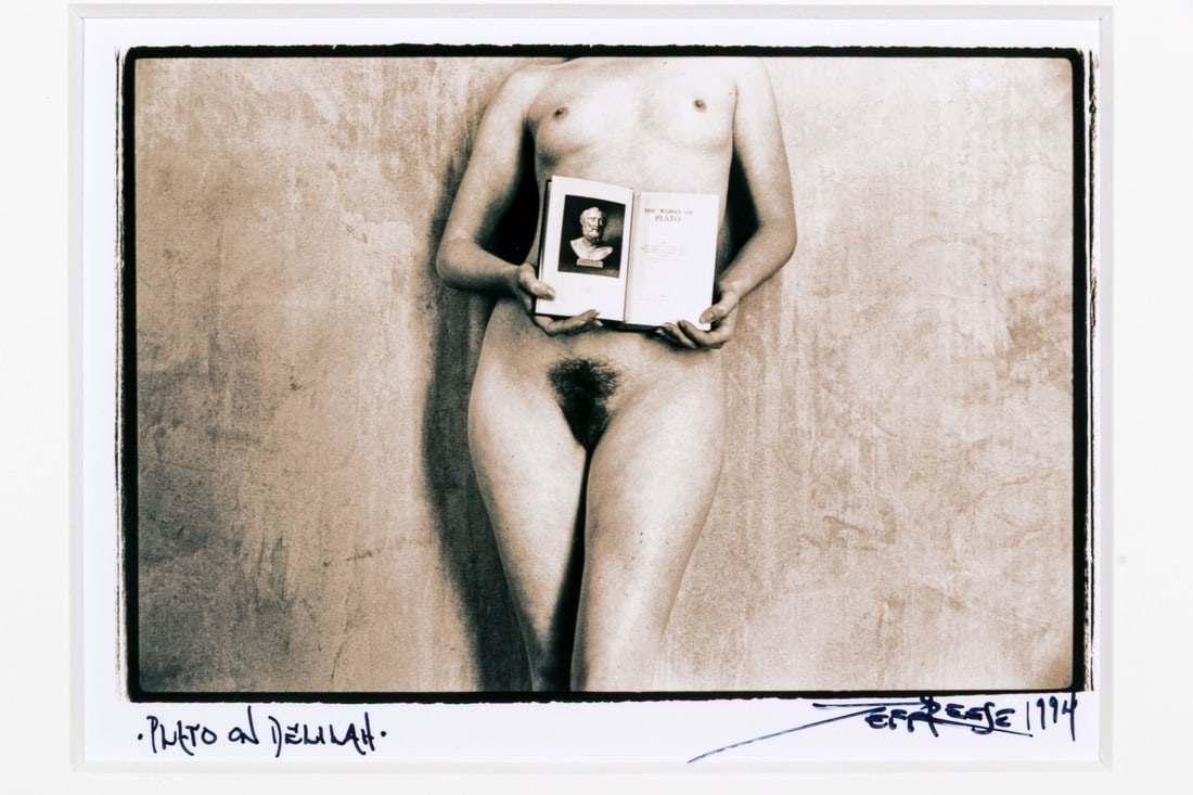 Jeff Reese (American, D. 2008) "Plato On Delilah" Signed Gelatin Silver Print, 1994: Jeff Reese (American, D. 2008) "Plato on Delilah" gelatin silver print depicting a female nude holding open a book on Plato with a view of a carved stone bust, leaning back against a gently textured w