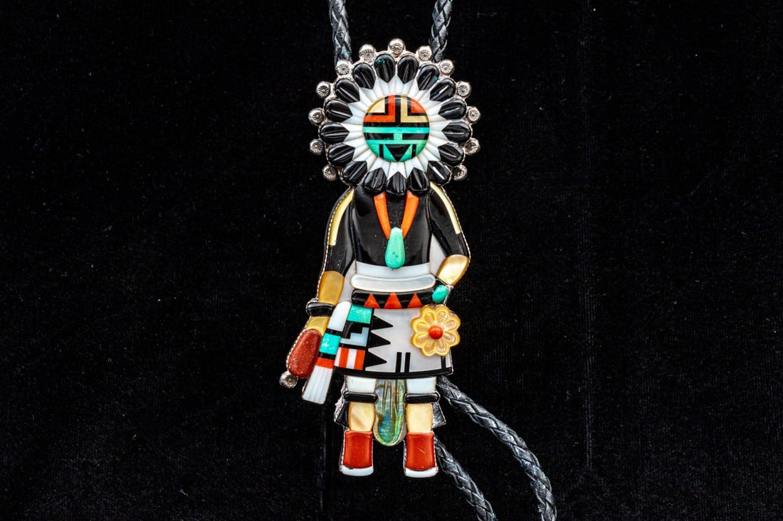 ZUNI ANDREW DEWA STERLING SILVER INLAID GIANT SUNFACE KACHINA BOLO, ON CORD: Zuni Andrew Dewa sterling silver inlaid giant sunface kachina bolo, on black leather cord, set with turquoise, mother-of-pearl, abalone, coral and onyx, finished with sterling silver bolo tips. "Andre