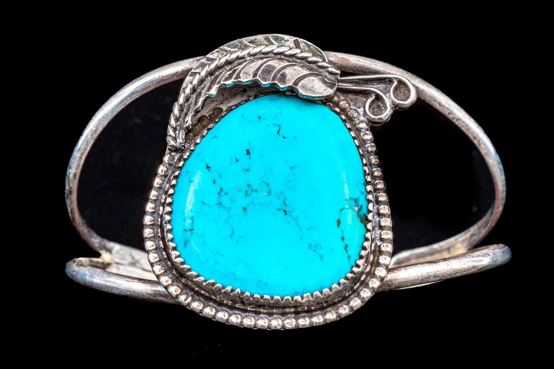 SOUTHWESTERN ULTRA WIDE FOLIATE AND TURQUOISE SET CUFF BRACELET: Southwestern ultra wide foliate and turquoise set cuff bracelet. This striking bracelet is 800 silver, featuring split sides and centering a large turquoise set center, with a foliate border Marks: No