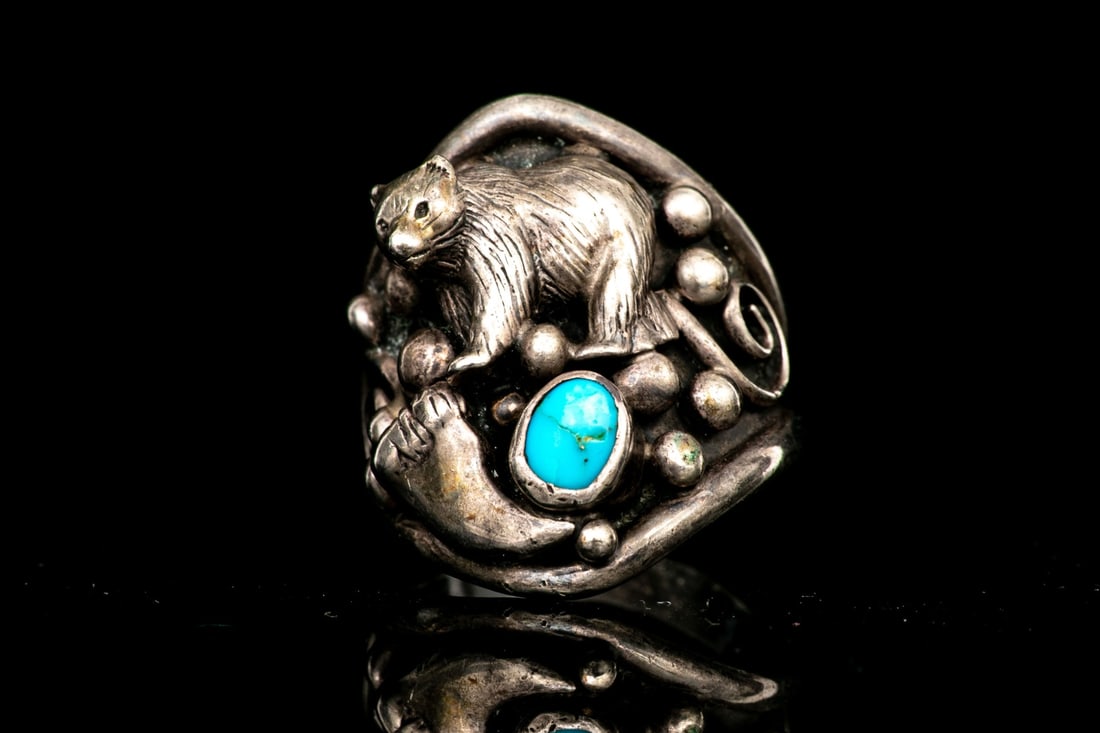 CAROL FELLEY STERLING SILVER FIGURAL BEAR AND TURQUOISE RING, CIRCA 1993, SIZE 9: This beautiful ring by Carol Felley from the Anglo Shop features a bear motif, over a tooth form and set with a cabachon turquoise, bezel set, finished with foliate patterning. Carol Felley graduated 