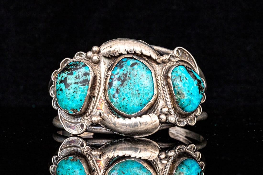 SOUTHWESTERN STERLING SILVER WIDE TURQUOISE SET CUFF BRACELET: This striking sterling silver bracelet has a Southwestern styling, featuring a wide profile set with three freeform style turquoise stones, finished with a handsome foliate top and open "Y" style shou