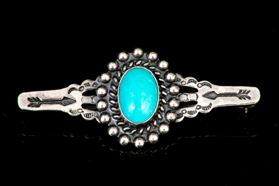SOUTHWESTERN STERLING SILVER OVAL TURQUOISE SET BAR PIN BROOCH: This handsome sterling silver Southwestern style brooch features an oval cabachon cut turquoise center, with braid and bead motif borders, decorated with arrow motif sides Marks: Sterling Dimensions: 