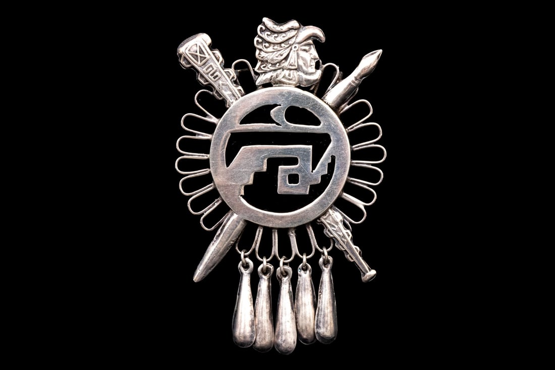 AZTEC MOTIF STERLING SILVER RAINCLOUD AND WARRIOR MOTIF BROOCH: This sterling silver Southwestern style brooch has a raincloud motif background, with an onyx and sterling Aztec motif center and topped with an Aztec warrior motif Marks: 925, GAV Dimensions: 3 1/2" 