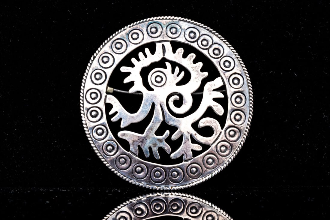 AZTEC STERLING SILVER OZOMATLI MONKEY MOTIF BROOCH/PENDANT: This sterling silver Aztec style brooch features an ozomatli monkey motif, finished with a circle motif border and a pendant style bale Marks: 925, signed Dimensions: 2 5/16" diameter Weight: 10.7