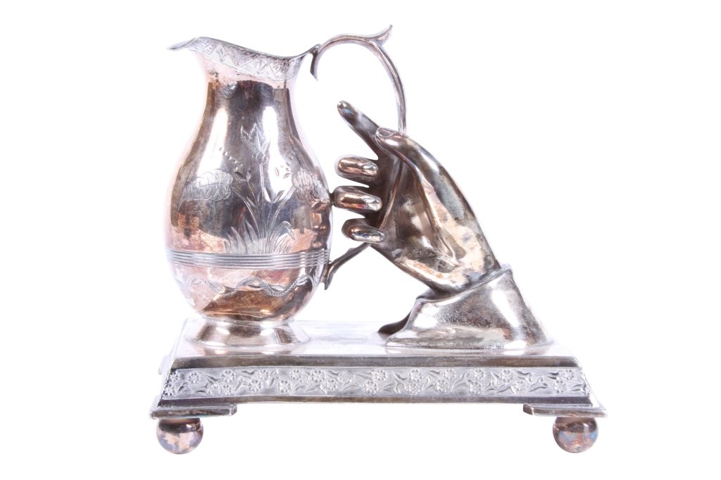 AN UNUSUAL VICTORIAN SILVERPLATED DESK ORNAMENT: Most probably a bud vase, in the form of a hand holding a pitcher, on a stand From the Estate of Thomas and Betty Mellon Evans