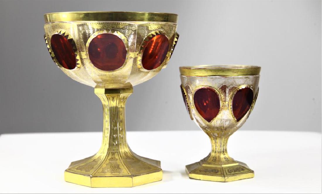 (1) ruby wine goblet and one (1) ruby chalice: One wine goblet with ruby tear-drop panels, gold gilding and gold enameling, six-sided base, and one chalice with ruby cabochons, gold gilding and gold enameling, octagonal base Goblet: 4 x 2 5/8 (bas