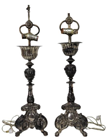(2) Baroque Style Silver Lamps: Two silver baroque style lamps with cherubs embossed at the middle. As is. Damage can be seen in photos.Size of each: 26 x 9 x 9 in.Please note that all sales are final. No refunds will be given under