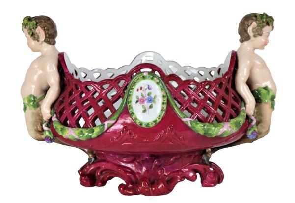 German Meissen Porcelain Centerpiece: German Meissen polychrome openwork centerpiece with young satyr-like figures standing on the rim, each figure holds a garland of encrusted flowers. Ca 1815 Meissen mark on the underside. Size: 11 x 7 