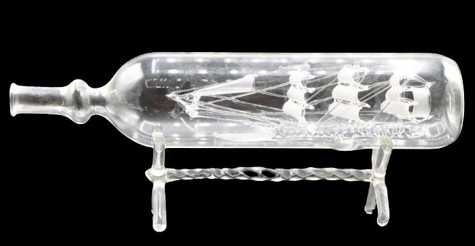 Blown Glass Ship in a Bottle: This is an intricate blown glass ship in a bottle with a glass stand. There is one small piece of the glass sail that has broken off inside the bottle. Size: 11 1/2 x 2 1/2 x 4 1/2 in. Please note tha