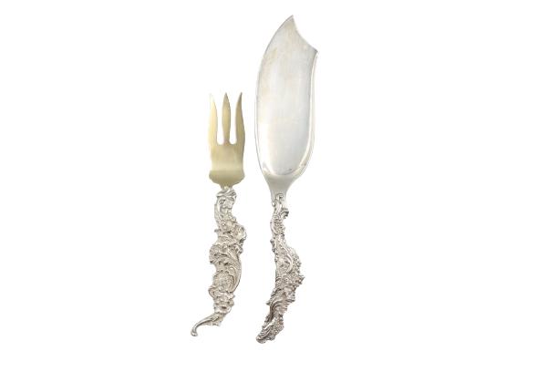 (2) Sheibler Sterling Serving Utensils, 9.74 OZT: (2) Sheibler Sterling Silver Serving Utensils. One knife and one fork. Marked on the underside shown in images. Intricate detail to the handles. Weight: 9.74 OZTSize: 13 x 2 1/2 in. #1559