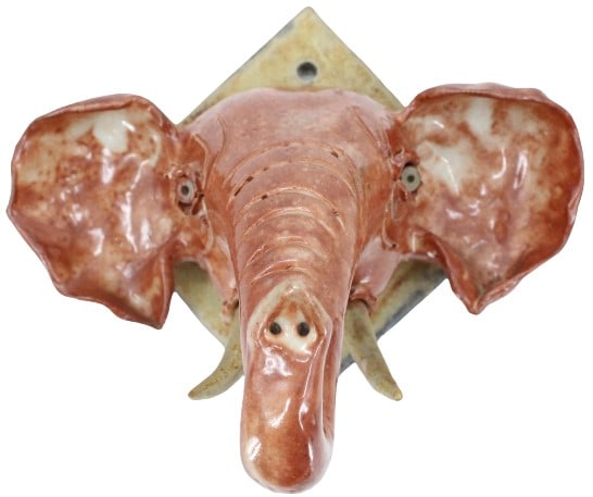 Ceramic Elephant Head: Ceramic Elephant Head. Hand made and hand painted head of an elephant on a diamond shaped tile to hang onto wall. Size: 6 1/2 x 5 1/2 x 5 3/4 in. #5289