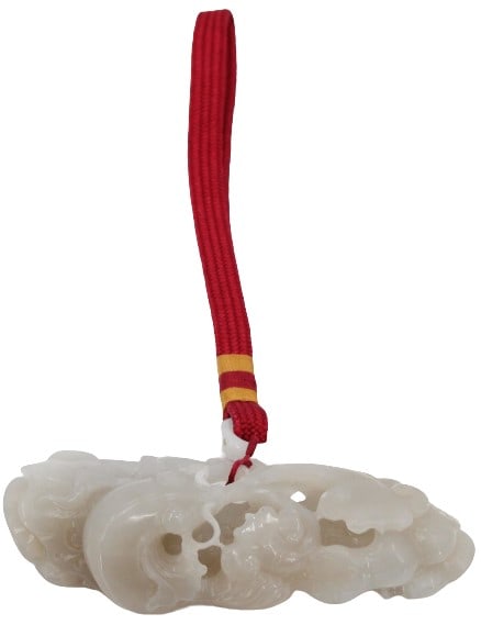 Carved White Jade with Red/Gold Tether: Carved white or purple jade botanical carving with red & gold fabric tetherSize: 4 1/8 x 7 1/2 x 1 1/2 in. with red tether. #5084